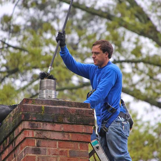 Chimney professional brushing a metal-capped flue