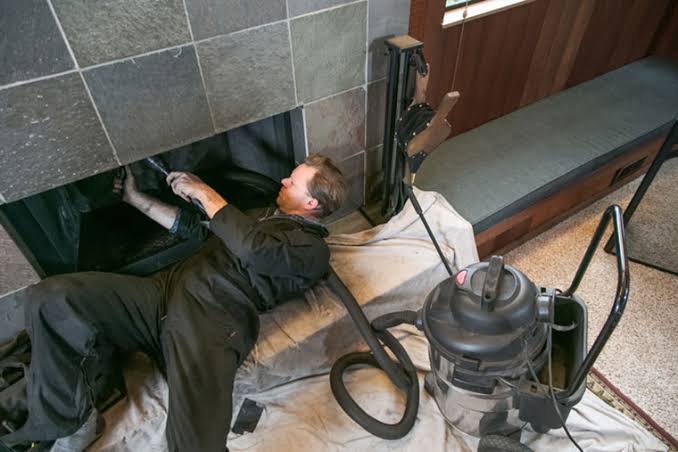 Technician vacuuming inside a residential fireplace